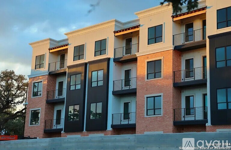 Apartment building with balconies and windows in front of a cloudy sky.
