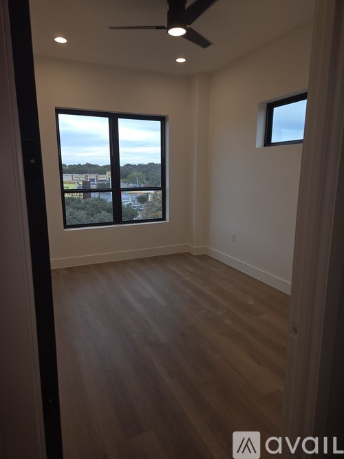 A room with a ceiling fan and a view of the outside through the window.