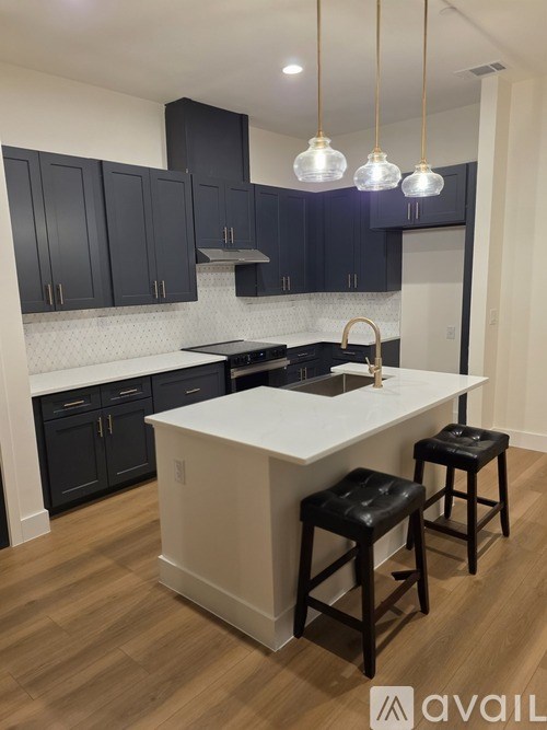 A kitchen with a white island and black bar stools.
