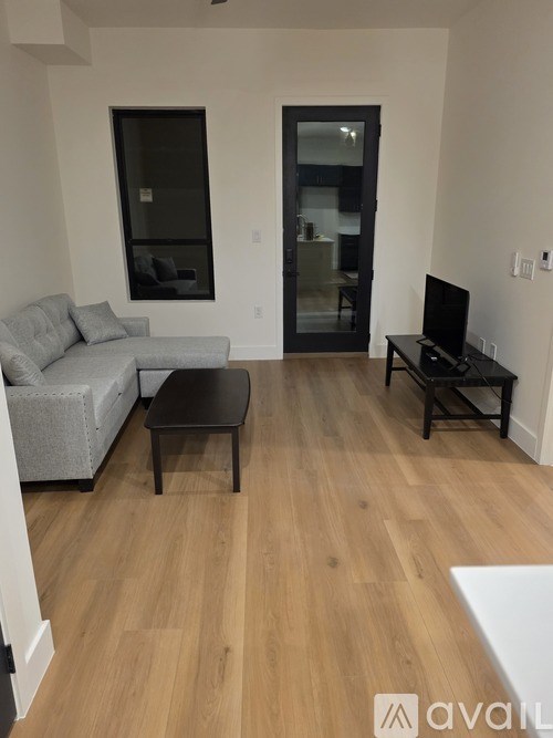 A living room with a grey couch, a black coffee table, and a television.