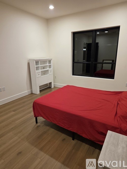 A bedroom with a red bedspread and a white wardrobe.