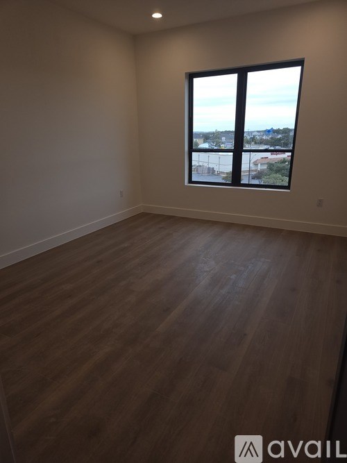 A room with wooden flooring and a large window overlooking a cityscape.