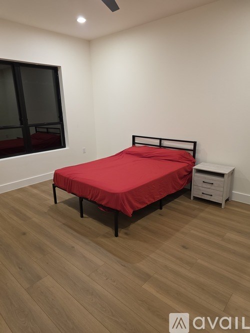 A bedroom with a red bedspread and a black bed frame.