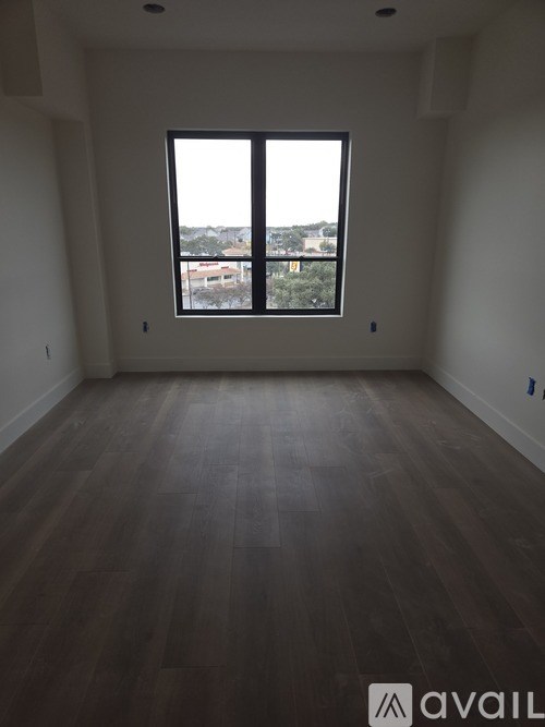 A room with a large window and wooden flooring.