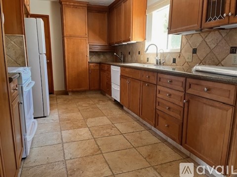 A kitchen with wooden cabinets and a tiled floor.