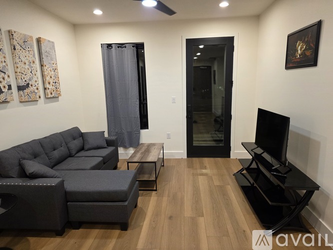 A spacious kitchen with dark grey cabinets and a wooden floor.