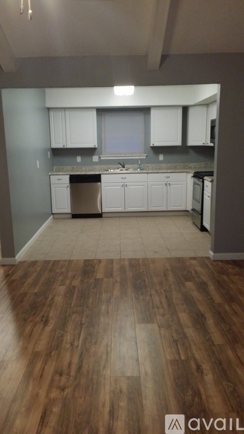 A kitchen with white cabinets and a wooden floor.