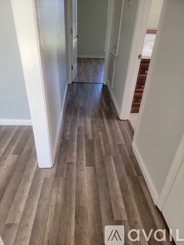 A hallway with wood flooring and white walls.