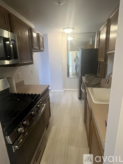 A kitchen with a black stove top oven and wooden cabinets.