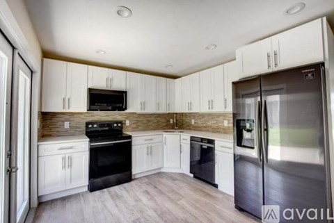 A kitchen with white cabinets and a black stove top oven.
