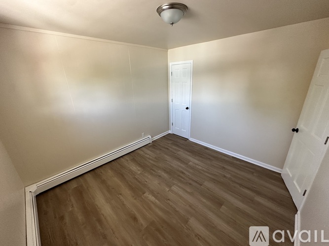 A room with wooden flooring and a white door.
