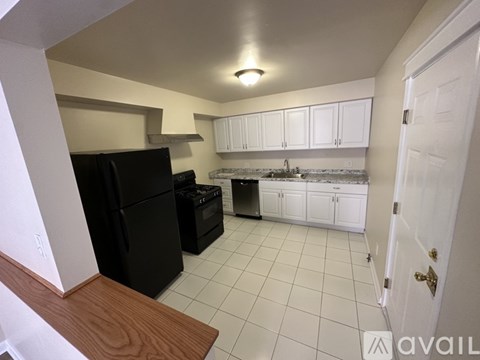 A kitchen with black appliances and white cabinets.