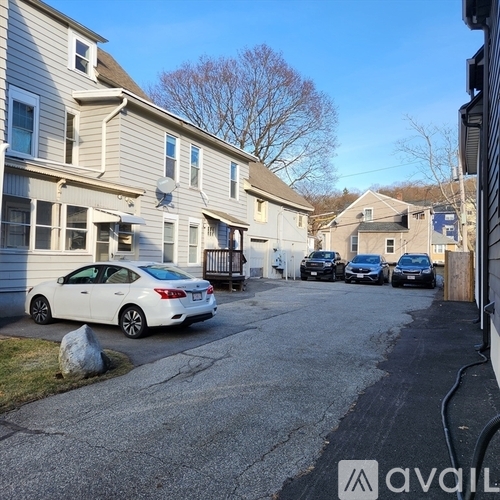 A white car is parked in a driveway in front of a house.