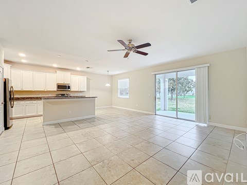 A spacious kitchen with white cabinets and a tiled floor.