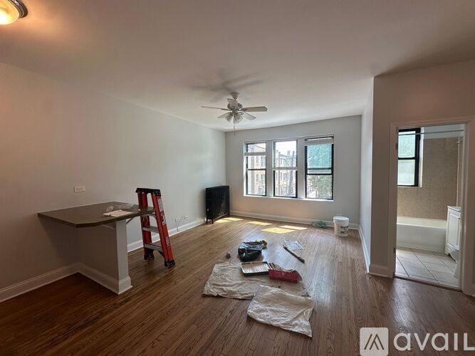 A room with a fan, a ladder, and some tools on the floor.