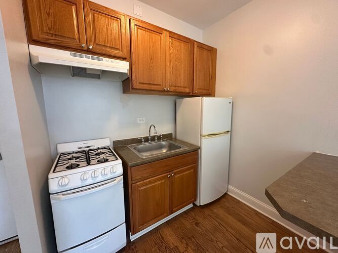 A small kitchen with a white stove, sink, and refrigerator.