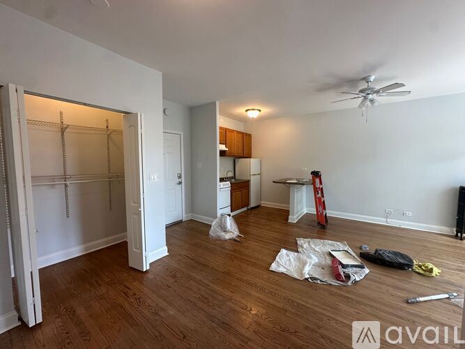 A room with wooden floors and a ceiling fan is under renovation.
