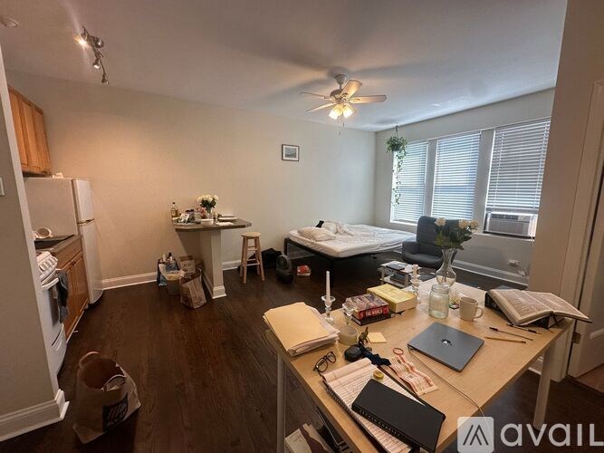 A room with a bed, desk, and a fan.