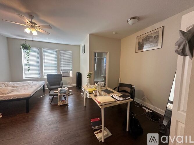 A room with a bed, desk, chair, and a ceiling fan.
