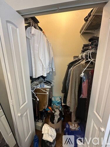 A small closet with clothes hanging on hangers.