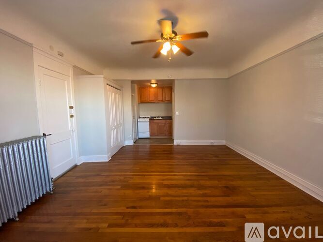 A spacious room with wooden floors and a ceiling fan.