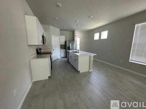 A kitchen with white cabinets and a wooden floor.