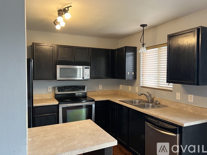 A kitchen with black cabinets and a stainless steel dishwasher.