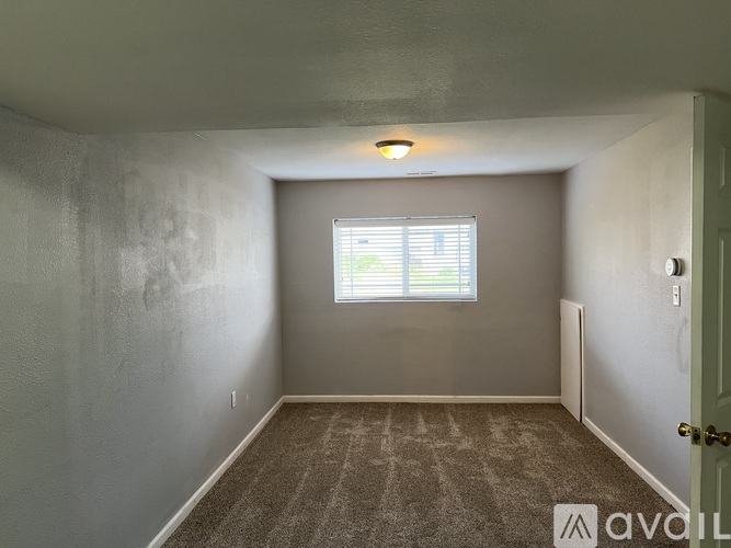 A room with a carpeted floor and a window with blinds.