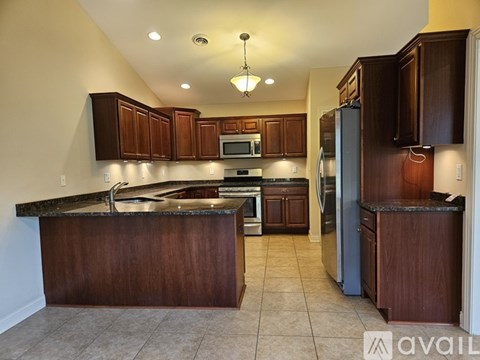 A kitchen with brown cabinets and a black fridge.