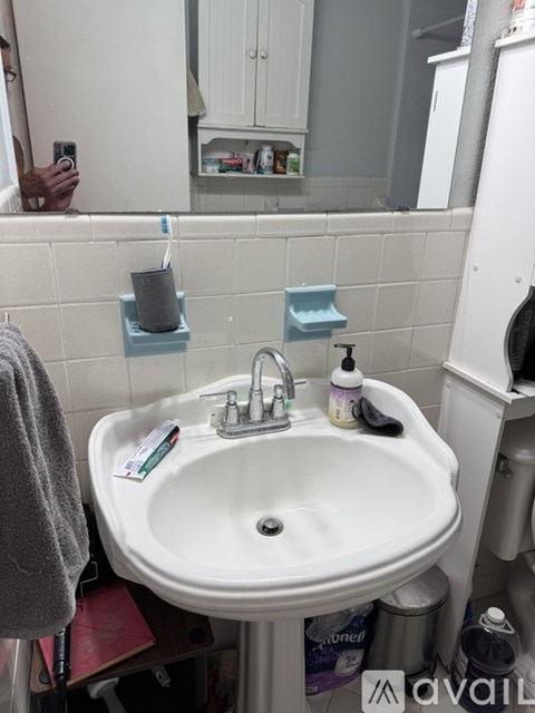 A bathroom sink with a grey towel hanging on the side.