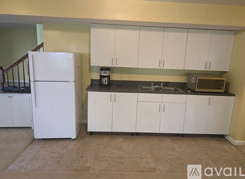 A kitchen with white cabinets and a white refrigerator.