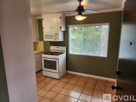 A kitchen with a white stove and white cabinets.