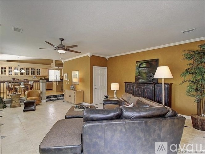 A living room with a black leather couch and a ceiling fan.