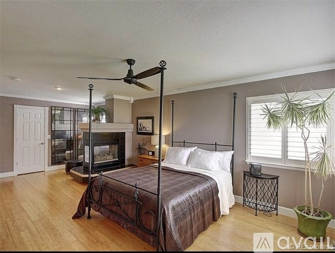 A bedroom with a large bed and a fireplace.