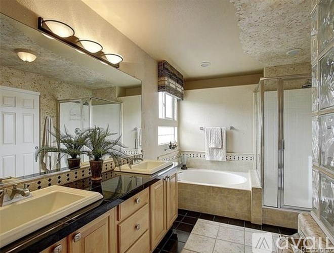 A bathroom with a large mirror, a sink, a bathtub, and a shower.
