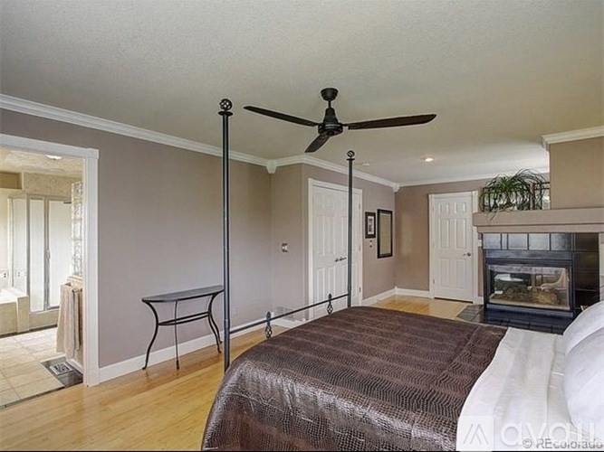 A bedroom with a bed, a table, and a fireplace.