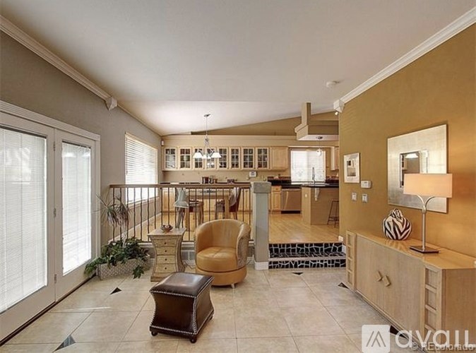 A well-lit, spacious living room with a balcony and a dining area in the background.