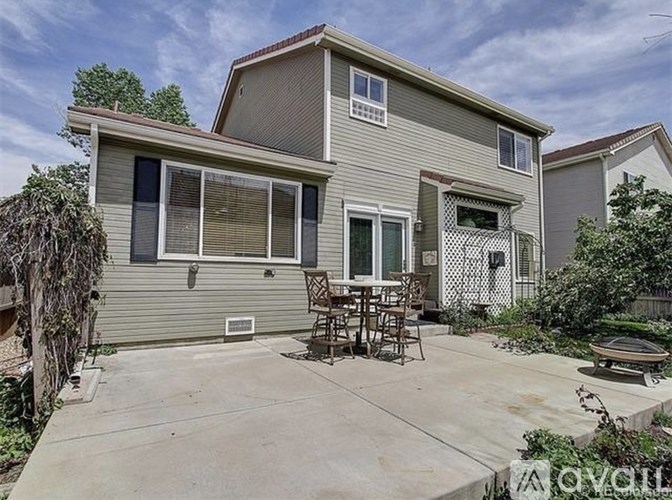 A house with a grey exterior and a patio with a table and chairs.