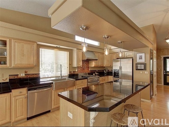 A kitchen with wooden cabinets and black countertops.