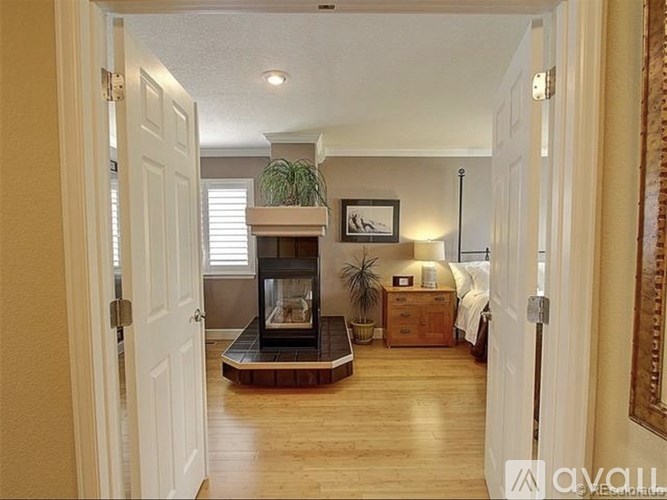 A living room with a fireplace and a bed in the background.
