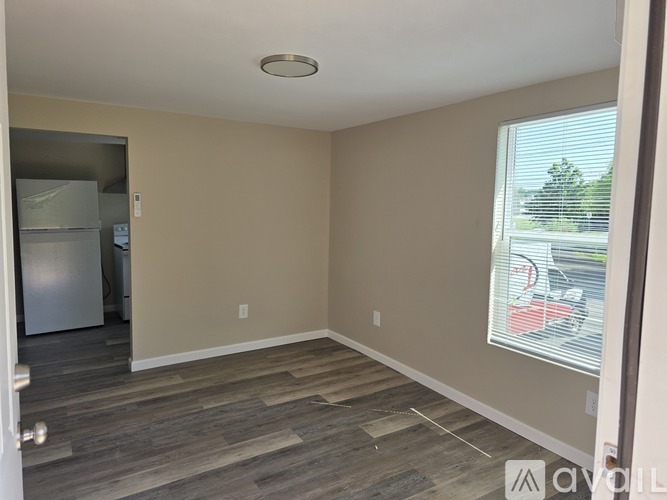 A room with a wooden floor and a window with blinds.