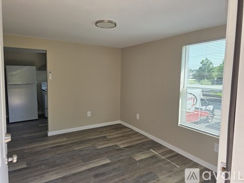 A room with a wooden floor and a window with blinds.