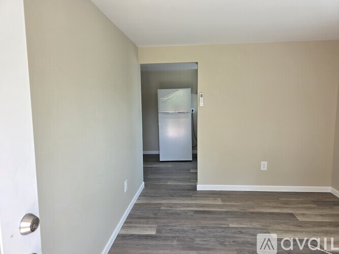 A room with a fridge and a door in the background.