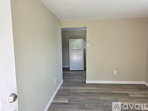 A room with a fridge and a door in the background.