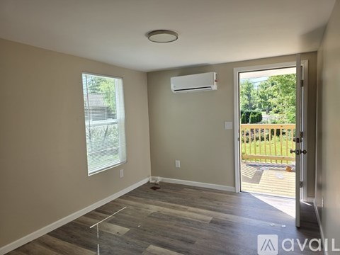 A room with a window, a door, and a wall-mounted air conditioner unit.