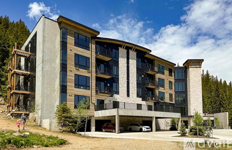 A modern concrete building with a balcony and a carport.