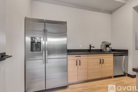 A stainless steel refrigerator in a kitchen with wooden cabinets.