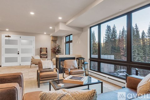A living room with a glass table and brown leather chairs.