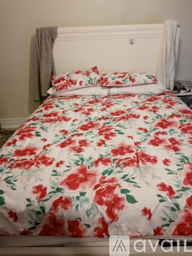 A floral bedspread covers a white bed with a white headboard.
