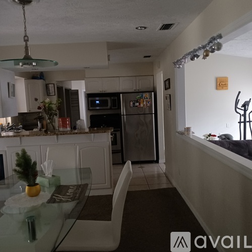 A kitchen with a glass table and a fridge.